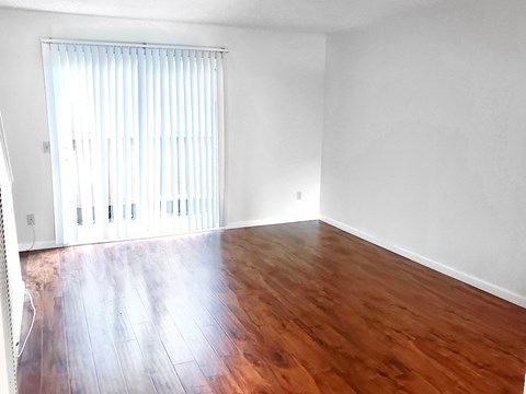 Empty living room interior with vinyl plank flooring and sliding door